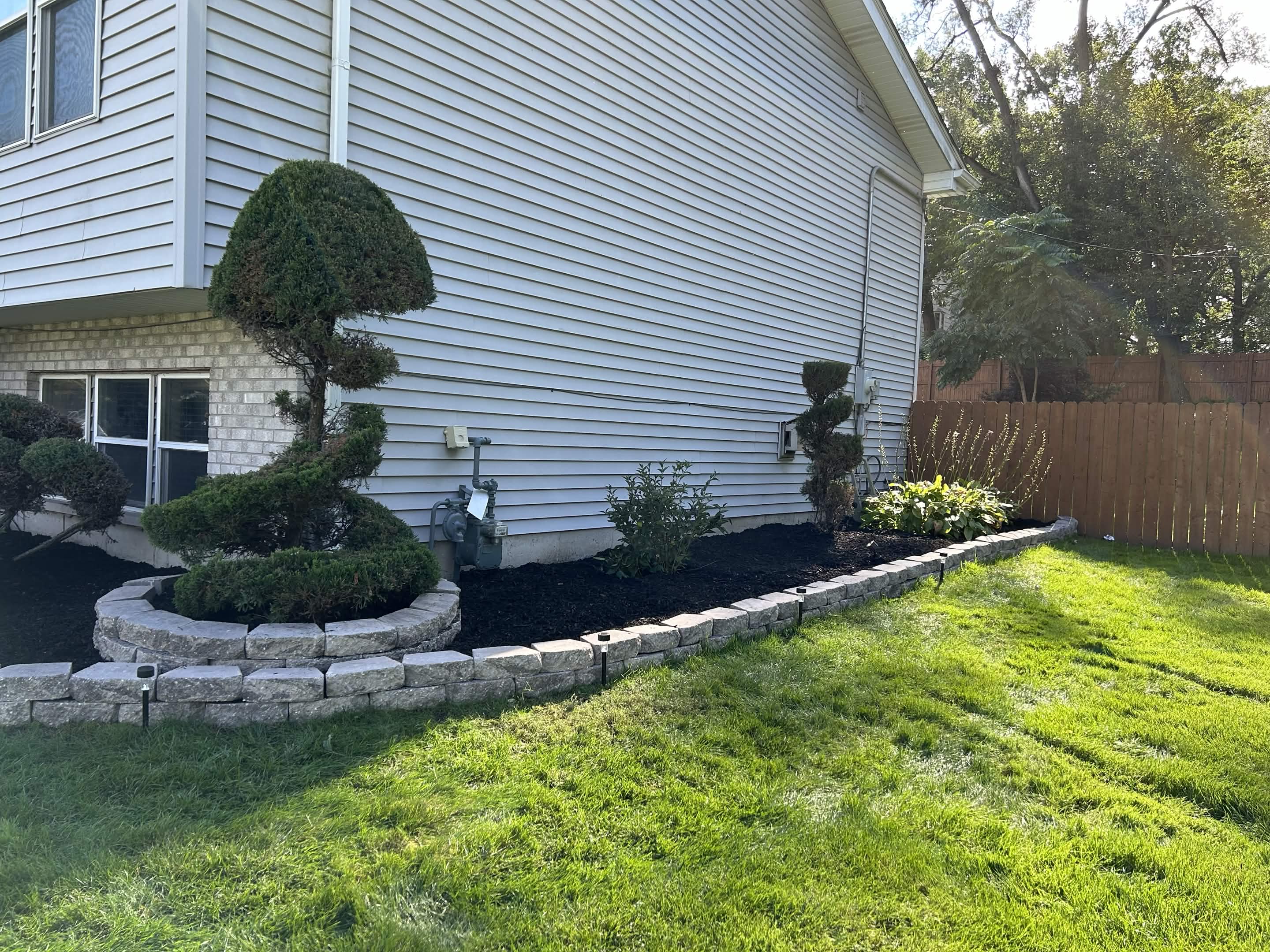 Garden bed refreshed with black mulch and lighting after cleanup